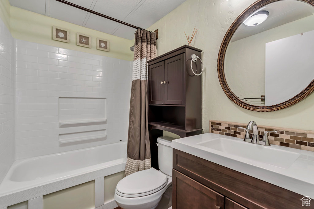Full bath with tasteful backsplash, toilet, vanity, and shower / bathtub combination with curtain