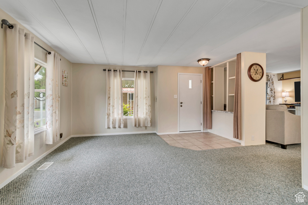 Tiled foyer with carpet and baseboards