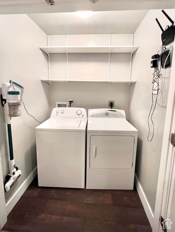 Laundry area featuring separate washer and dryer, baseboards, and dark wood finished floors