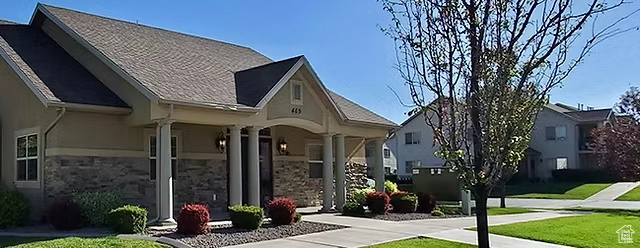 Back of property with covered porch, stone siding, and a yard