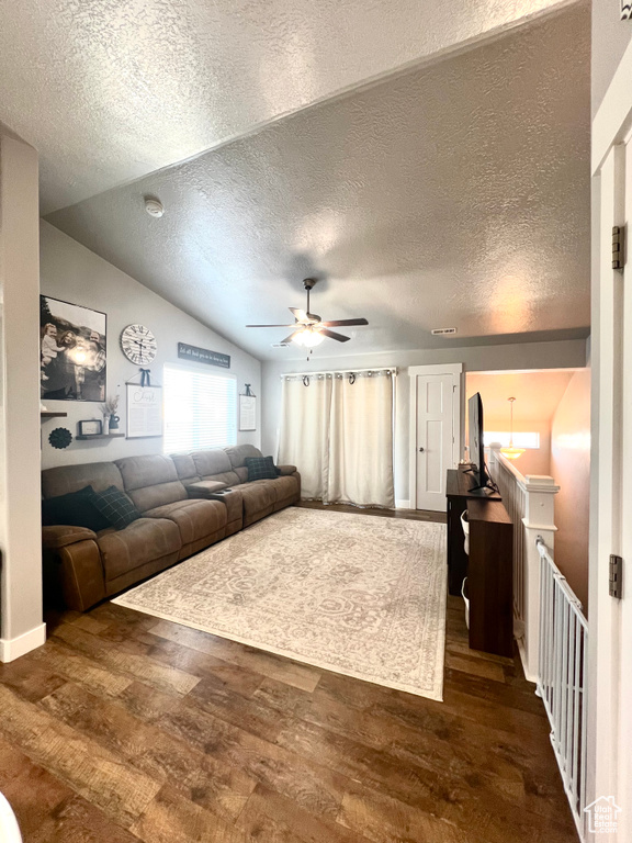 Living area featuring wood finished floors, a ceiling fan, a textured ceiling, and vaulted ceiling