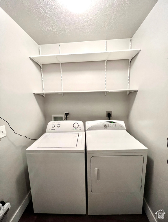Laundry area with washing machine and clothes dryer, baseboards, and a textured ceiling
