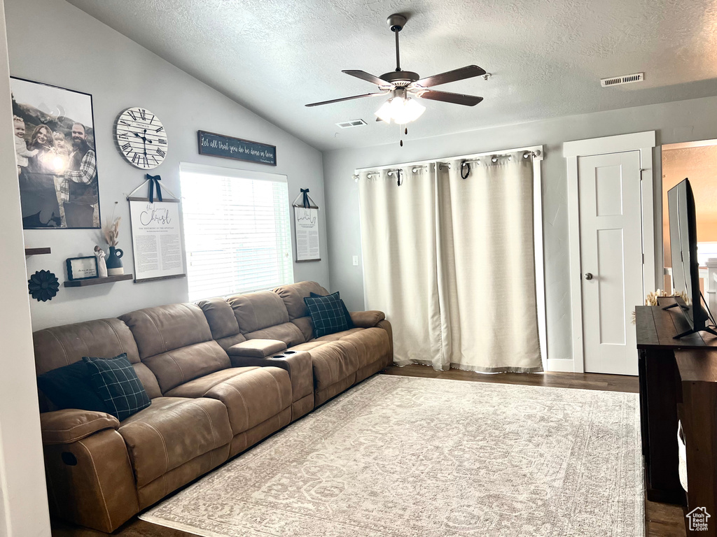 Living area featuring vaulted ceiling, wood finished floors, ceiling fan, and a textured ceiling