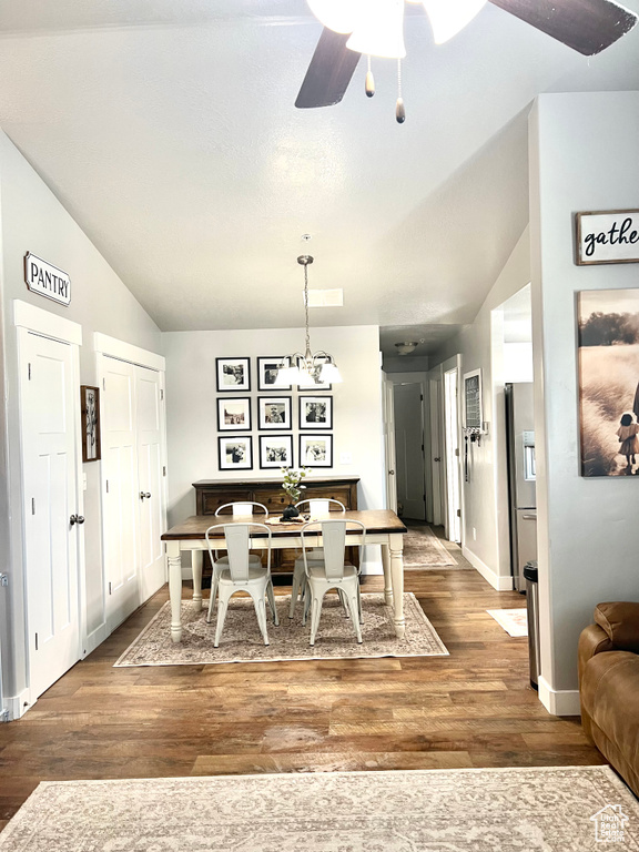 Dining space featuring lofted ceiling, ceiling fan, wood finished floors, baseboards, and a chandelier