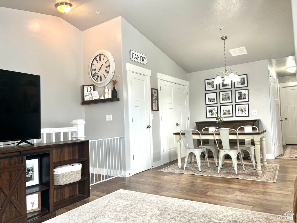 Dining space featuring vaulted ceiling, a chandelier, and wood finished floors