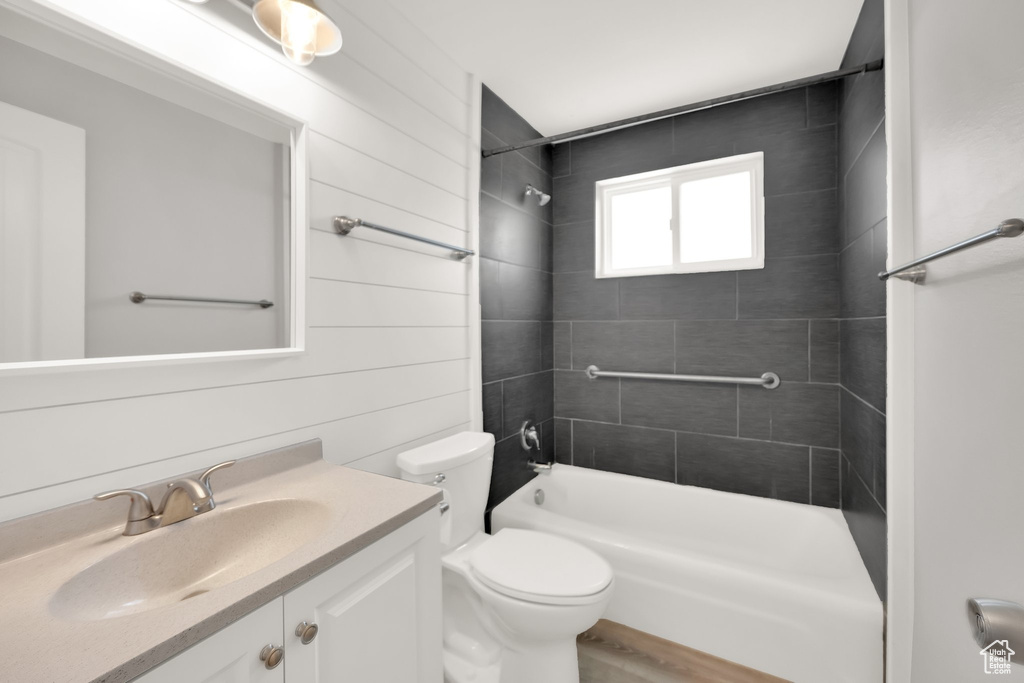 Bathroom featuring toilet, shower / bath combination, vanity, and wood finished floors
