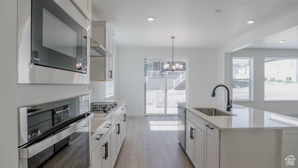 Kitchen with stainless steel appliances, healthy amount of natural light, light countertops, a chandelier, and recessed lighting