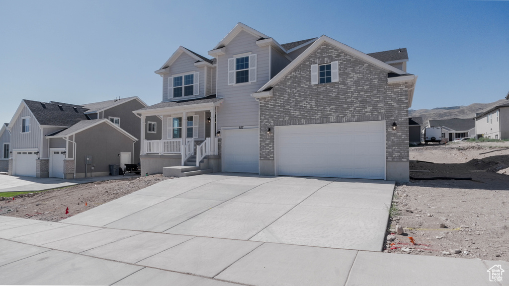 View of front of home with a garage, brick siding, concrete driveway, a residential view, and a porch