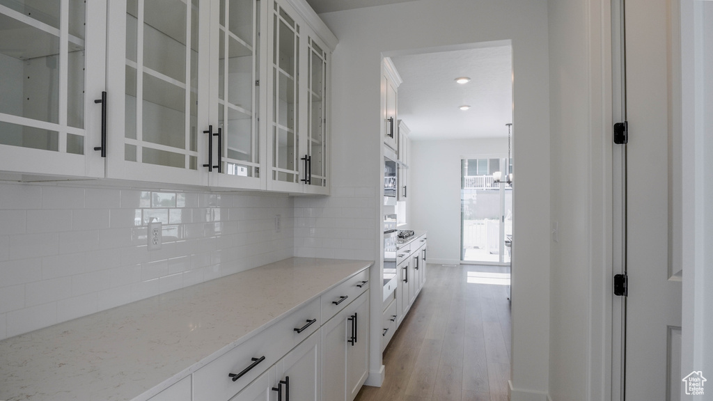 Bar featuring decorative backsplash, a chandelier, and light wood-style flooring