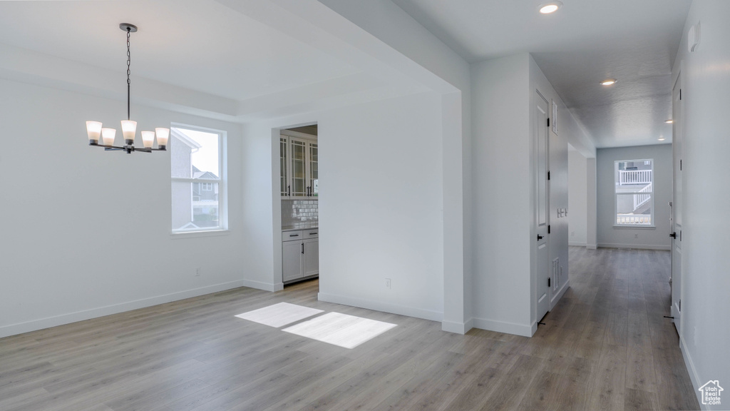 Unfurnished dining area with a chandelier, light wood-style flooring, and recessed lighting