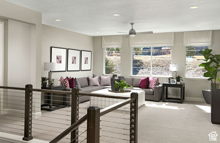 Carpeted living room featuring recessed lighting, a textured ceiling, ceiling fan, and baseboards