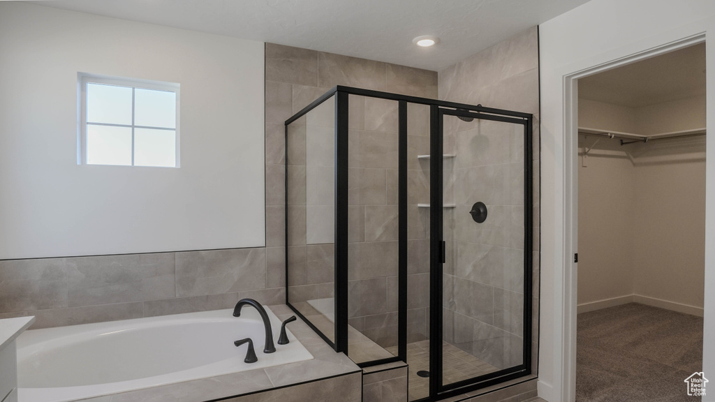 Full bathroom with a bath, a shower stall, and a walk in closet