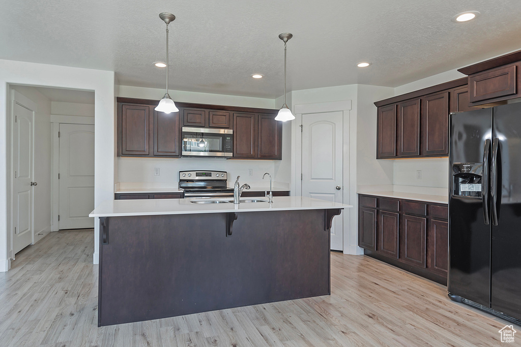 Kitchen with light countertops, appliances with stainless steel finishes, a sink, and light wood-type flooring