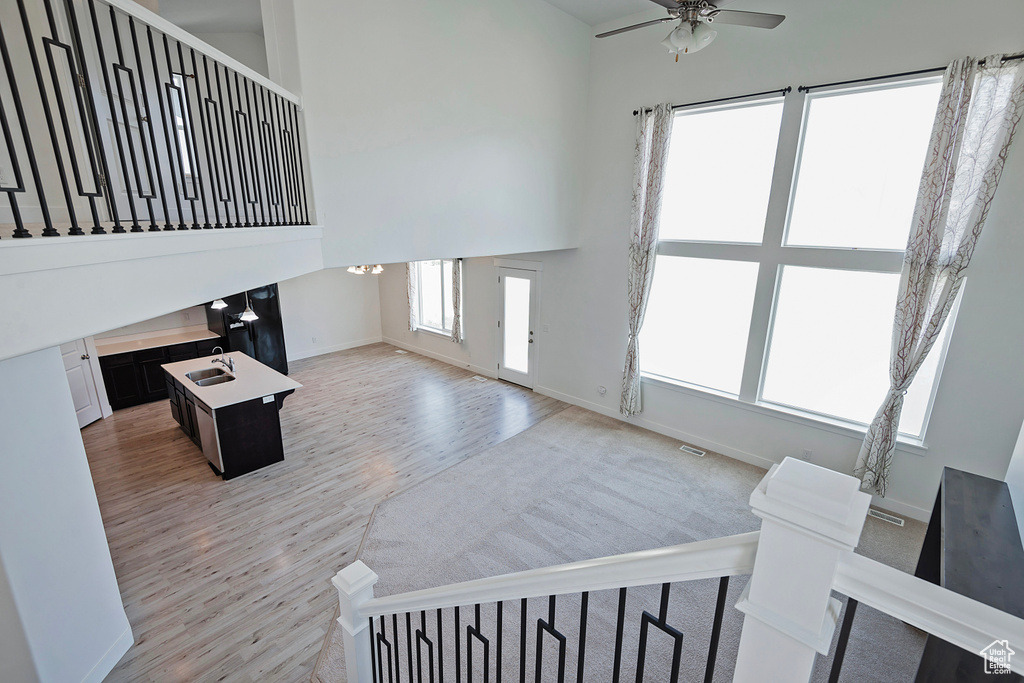 Unfurnished living room featuring a sink, baseboards, ceiling fan, and light wood-type flooring