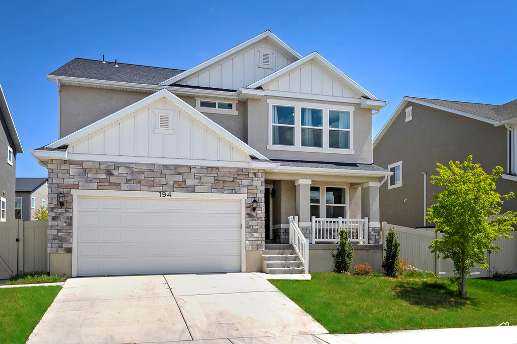 Craftsman-style home featuring concrete driveway, board and batten siding, a porch, and fence