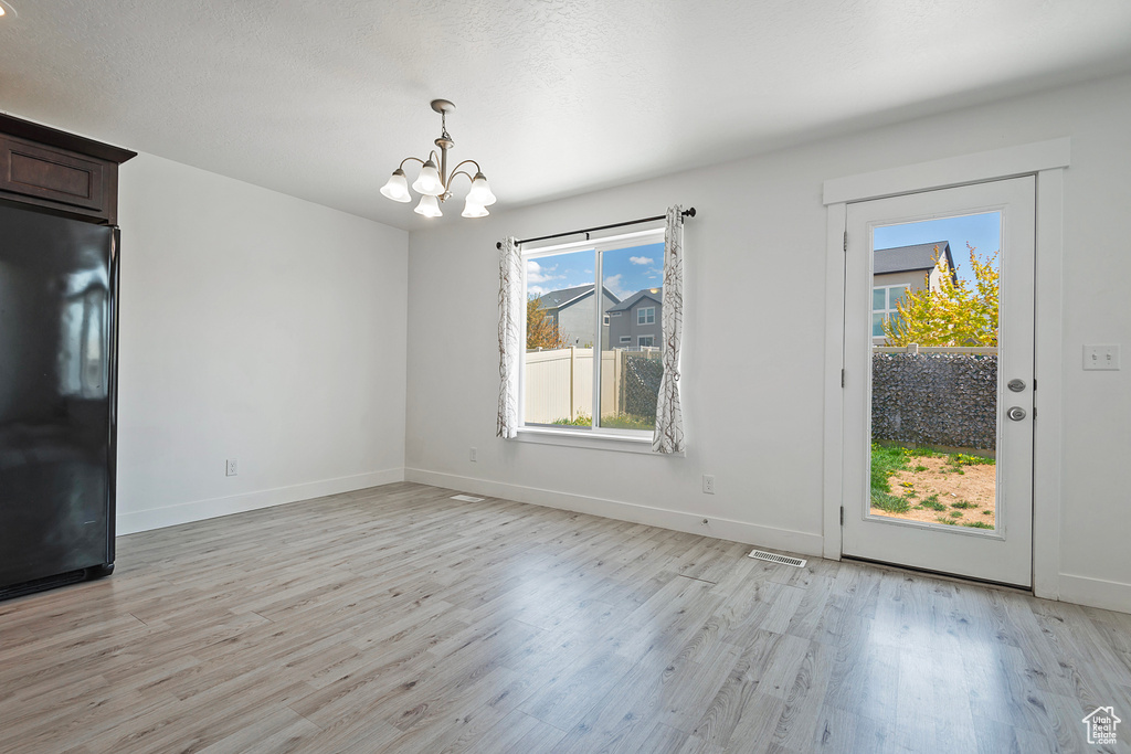Unfurnished dining area with light wood-style floors, baseboards, a chandelier, and visible vents