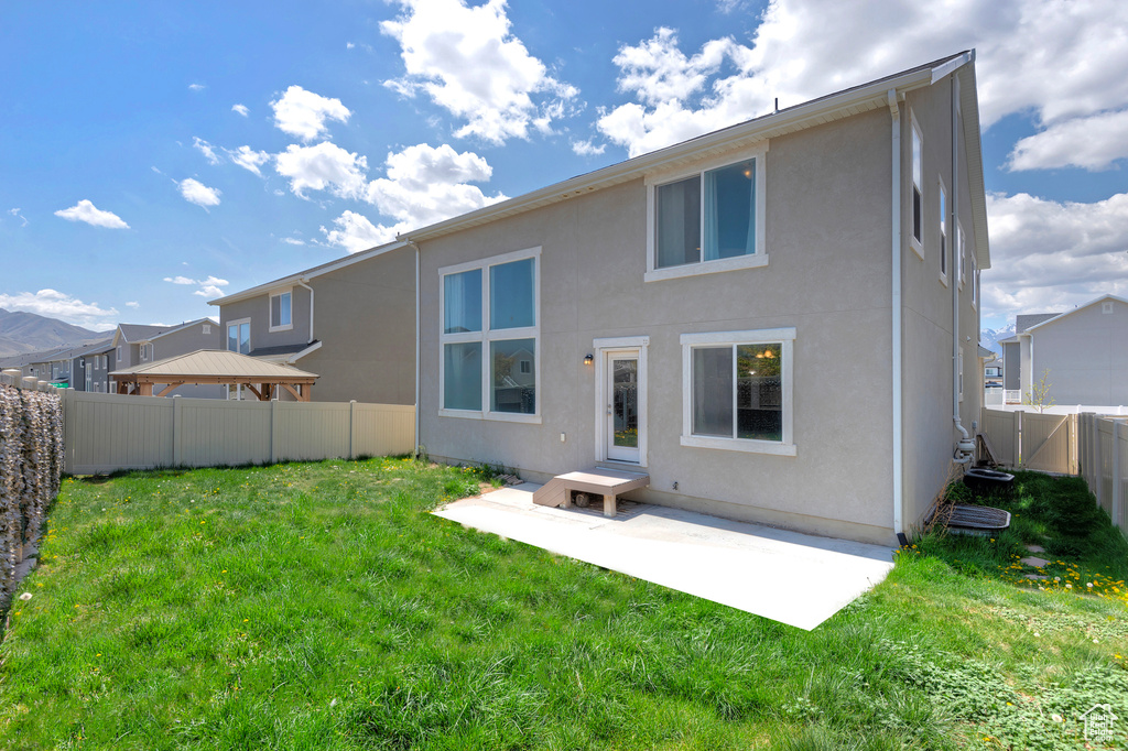Back of house with a lawn, a fenced backyard, a patio area, and stucco siding