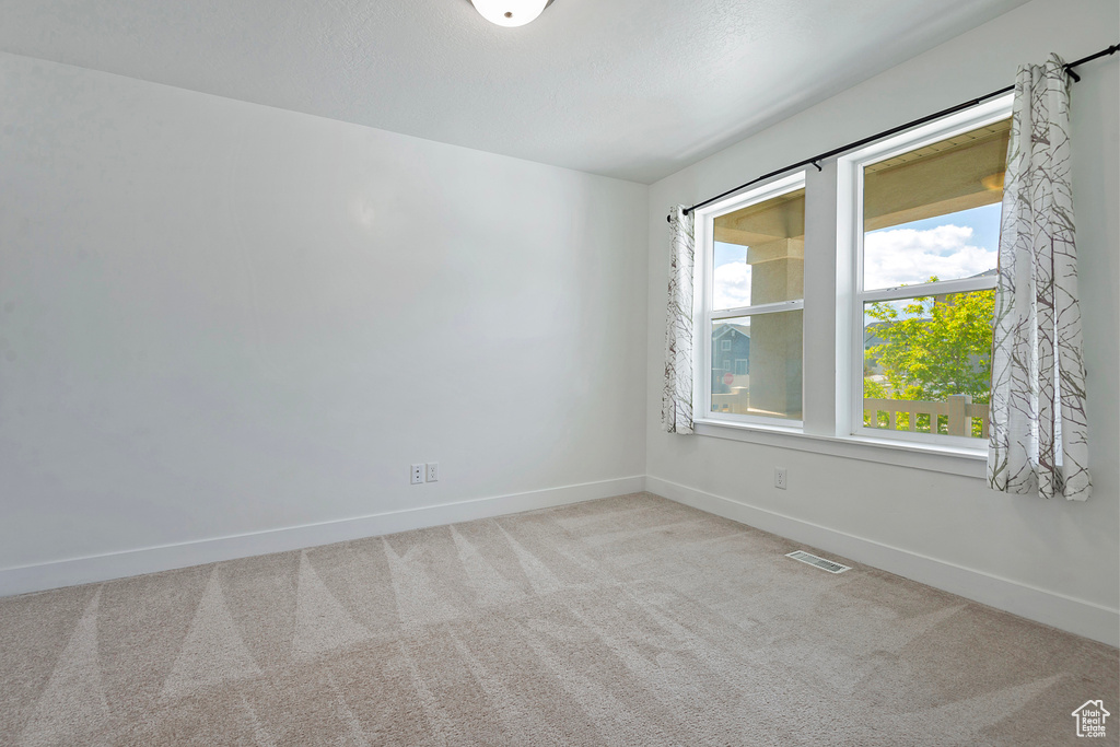 Carpeted empty room featuring baseboards and visible vents