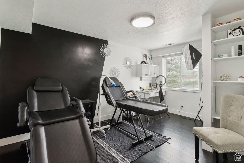 Office space with a textured ceiling, wood finished floors, and baseboards