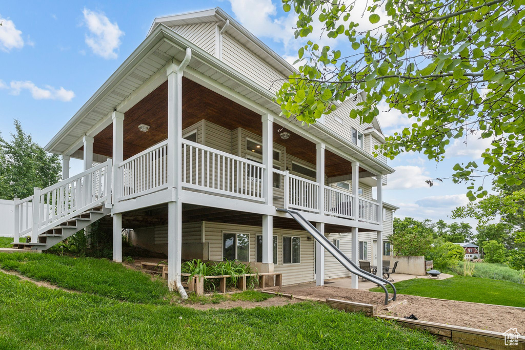 Rear view of house featuring a lawn, stairway, and a patio