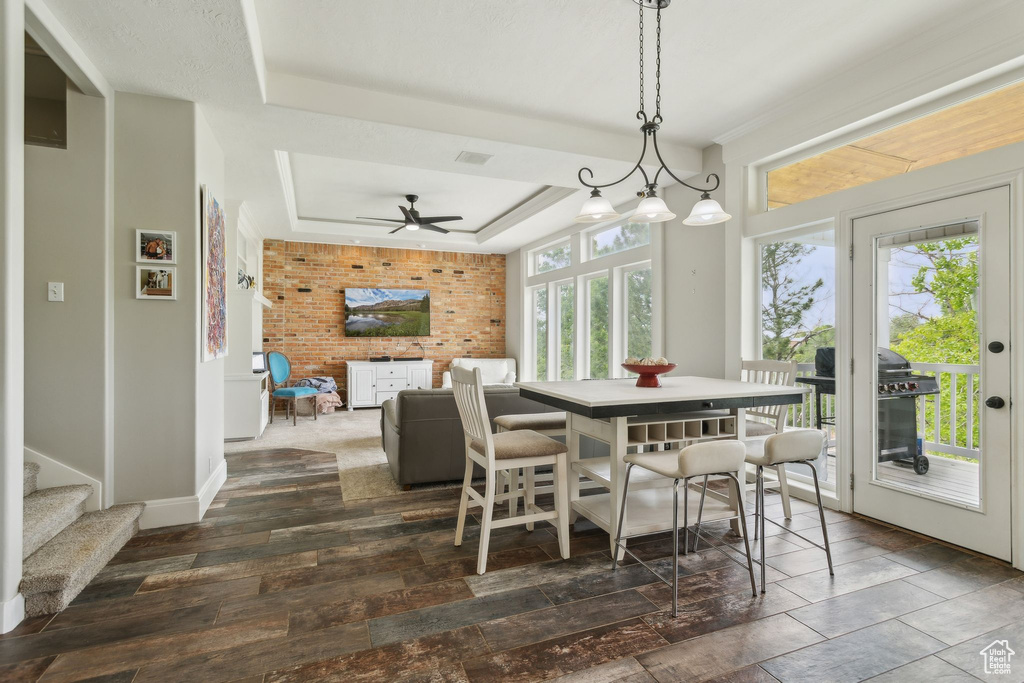 Dining area with a raised ceiling, ceiling fan, and baseboards