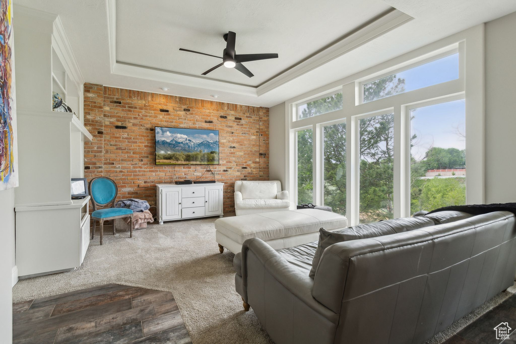 Living area with a raised ceiling, ceiling fan, and ornamental molding