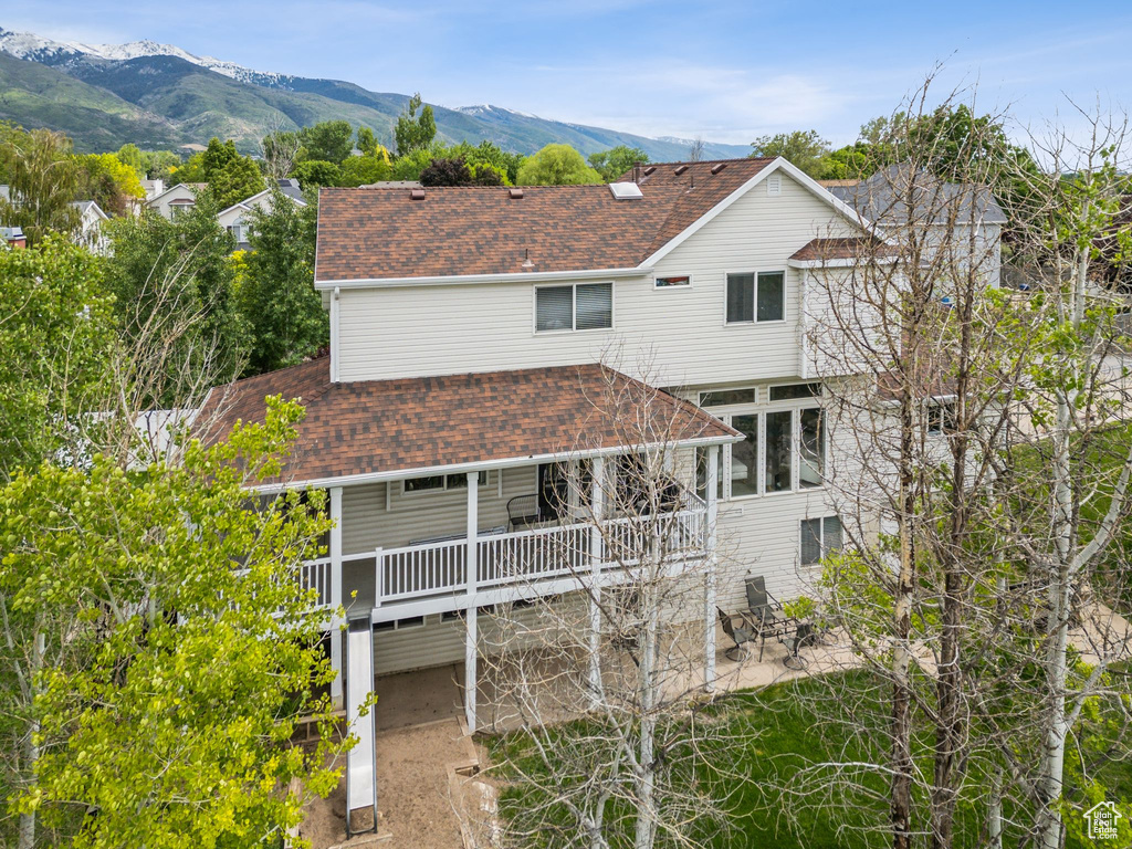 Back of property featuring a shingled roof, a patio, and a deck with mountain view