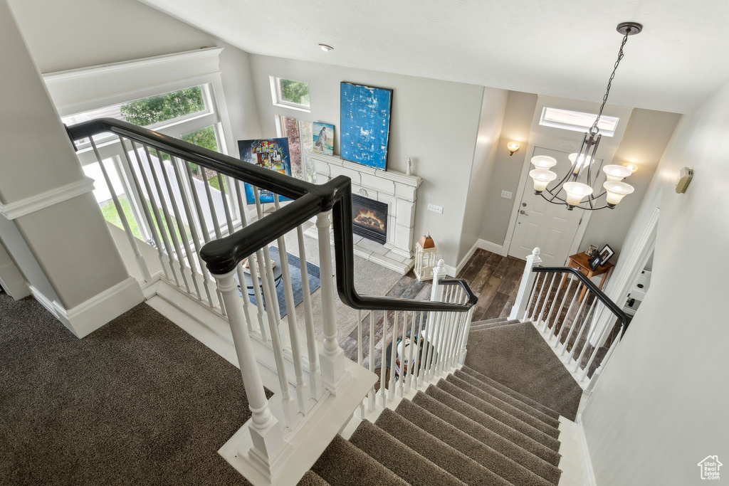 Stairway featuring baseboards, a glass covered fireplace, wood finished floors, and carpet
