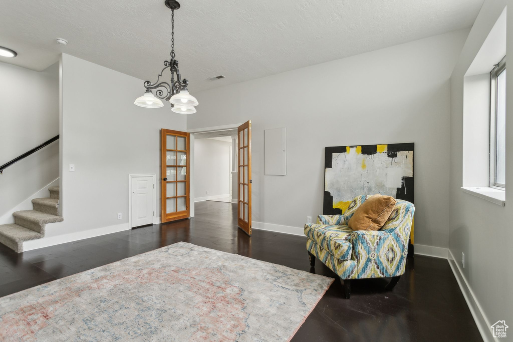 Living area with french doors, baseboards, stairs, dark wood-style floors, and a chandelier