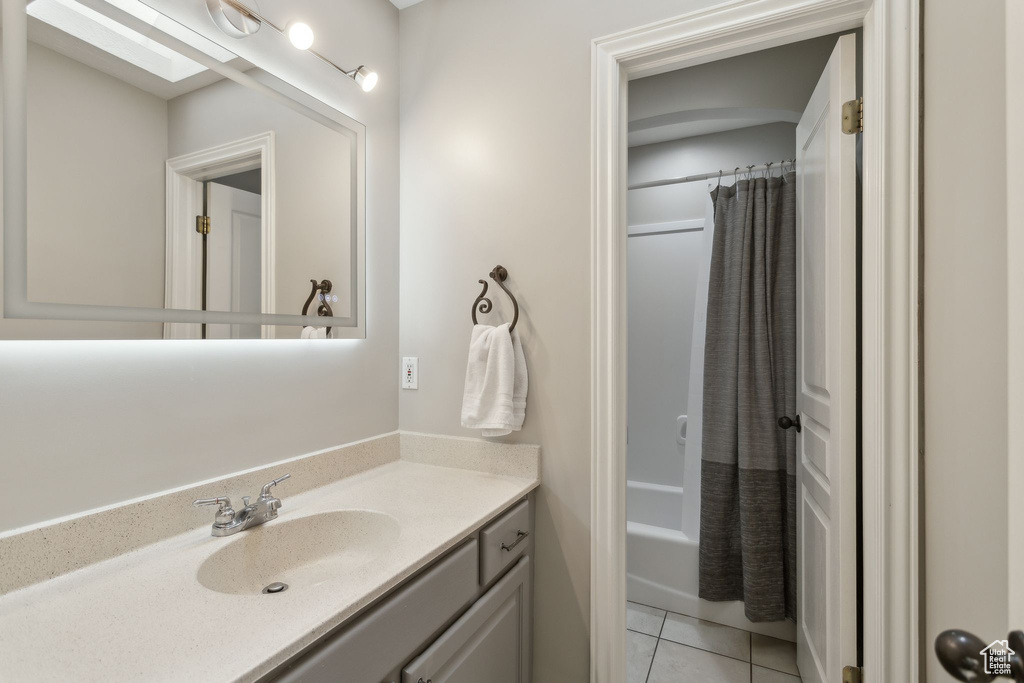 Bathroom featuring vanity, tile patterned floors, shower / bath combination with curtain, and a skylight