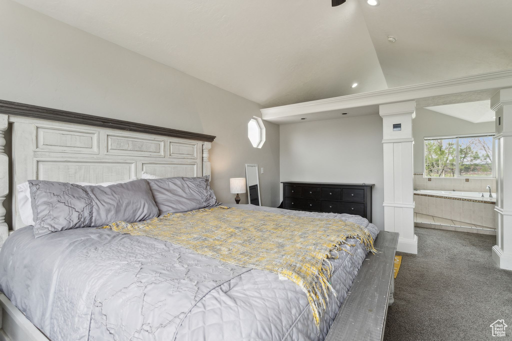Carpeted bedroom featuring lofted ceiling, multiple windows, ensuite bathroom, and decorative columns