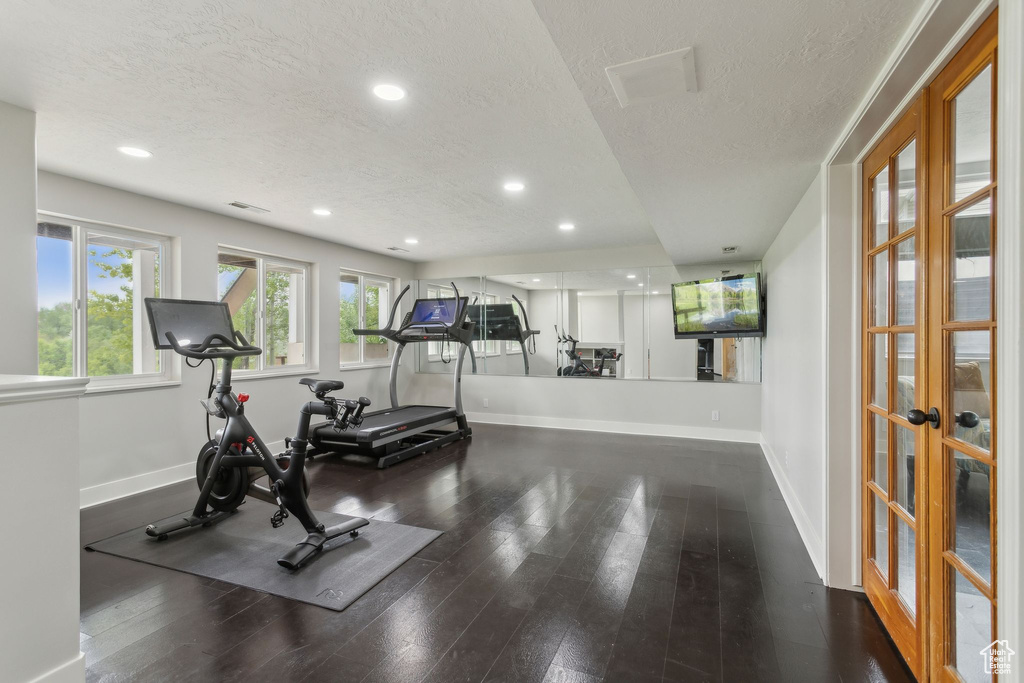 Exercise room with a textured ceiling, french doors, baseboards, wood finished floors, and recessed lighting