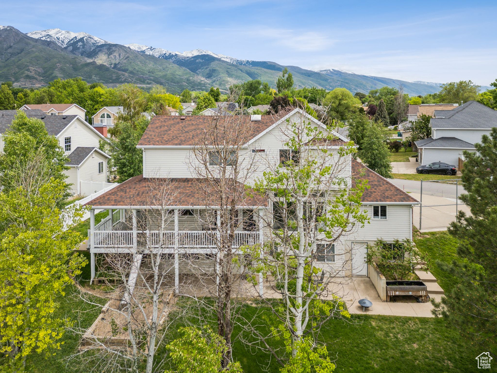 Back of property with a residential view, roof with shingles, a mountain view, and a patio area