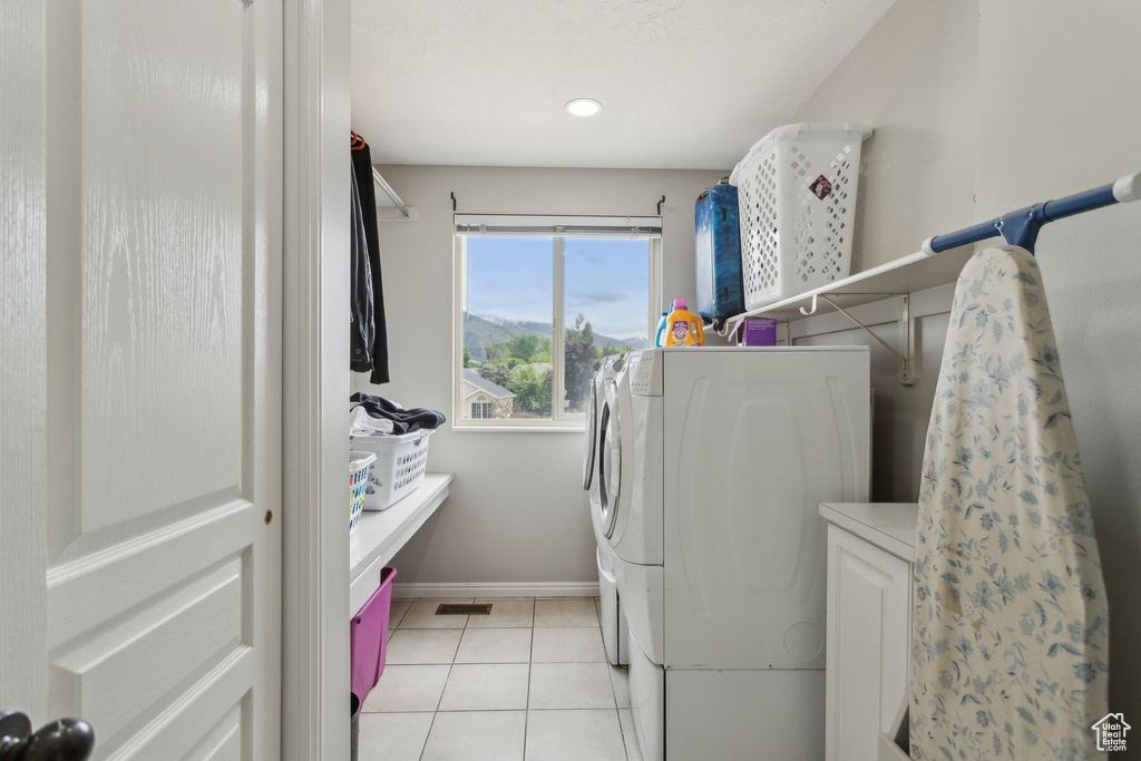 Laundry area with separate washer and dryer, baseboards, and light tile patterned floors
