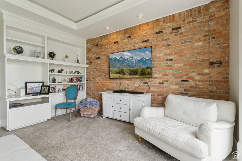 Living area featuring carpet, brick wall, built in shelves, and ornamental molding