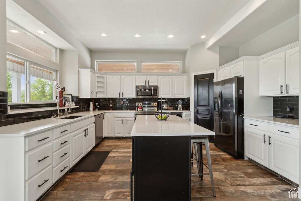 Kitchen with appliances with stainless steel finishes, a sink, tasteful backsplash, recessed lighting, and a kitchen island