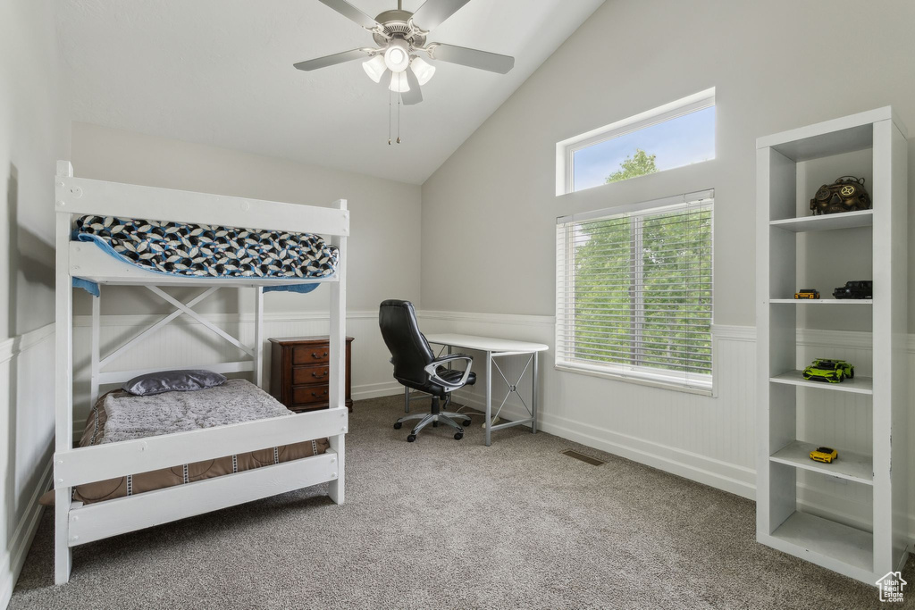 Carpeted bedroom featuring wainscoting, high vaulted ceiling, and ceiling fan