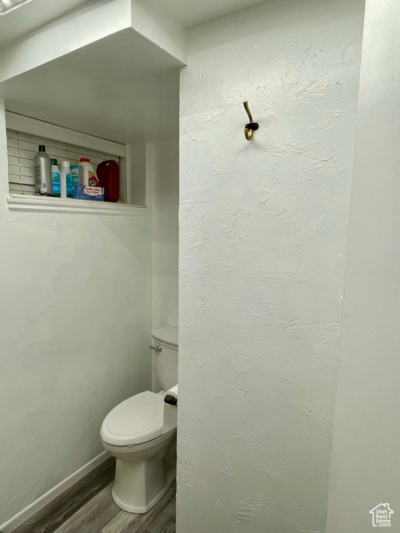 Bathroom featuring wood finished floors, toilet, and baseboards