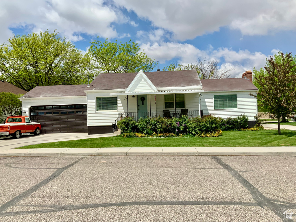 View of front of house featuring a front lawn, a garage, a porch, and concrete driveway