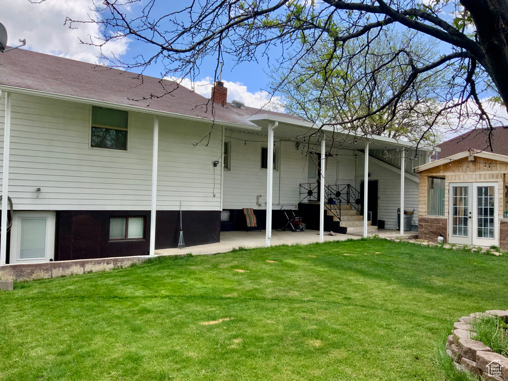 Back of house with french doors, a lawn, and a chimney