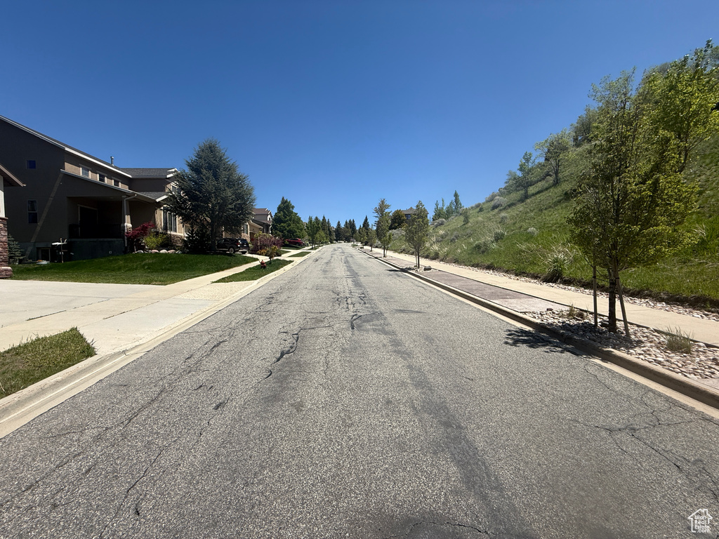 View of asphalt road featuring curbs and sidewalks