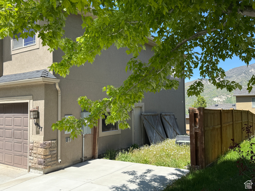 View of property exterior featuring stucco siding, stone siding, a garage, and a mountain view