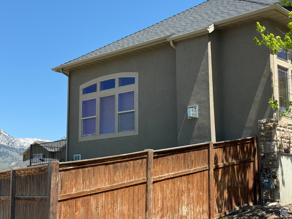 View of property exterior featuring roof with shingles, stucco siding, and a mountain view