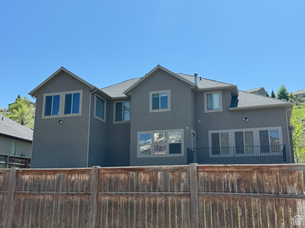 Back of property with stucco siding and roof with shingles