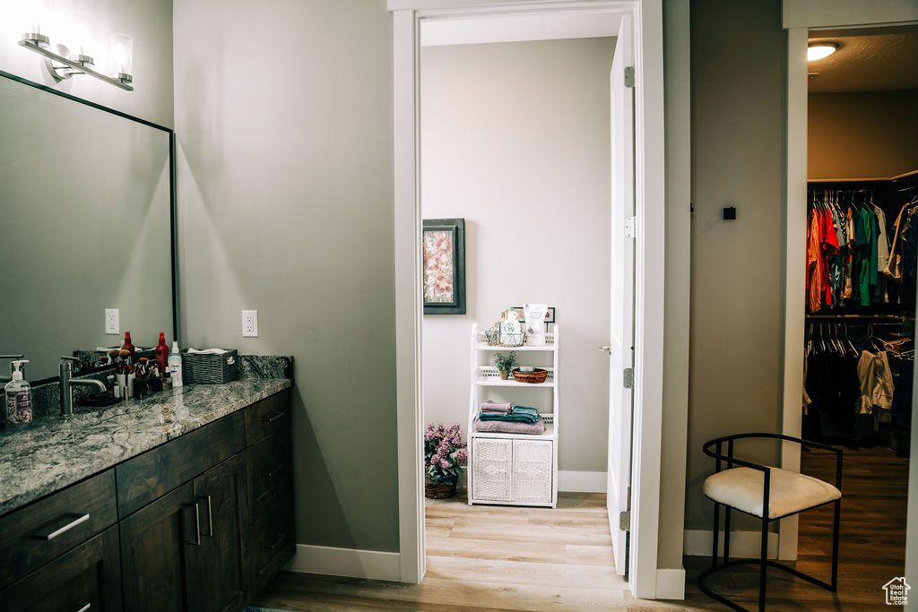 Bathroom featuring wood finished floors, baseboards, vanity, and a walk in closet
