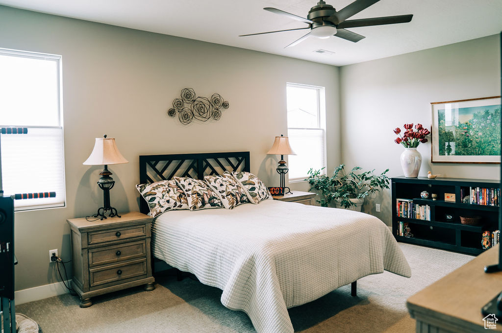 Bedroom with light carpet, ceiling fan, and baseboards