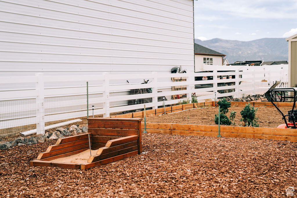 View of home's exterior featuring a garden, a mountain view, and fence