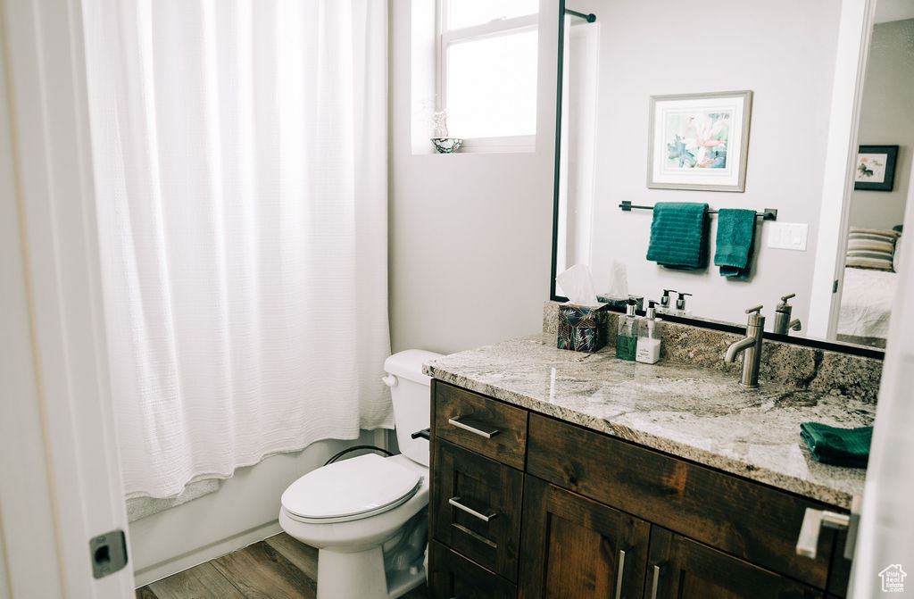 Bathroom with toilet, wood finished floors, vanity, and shower / bath combo