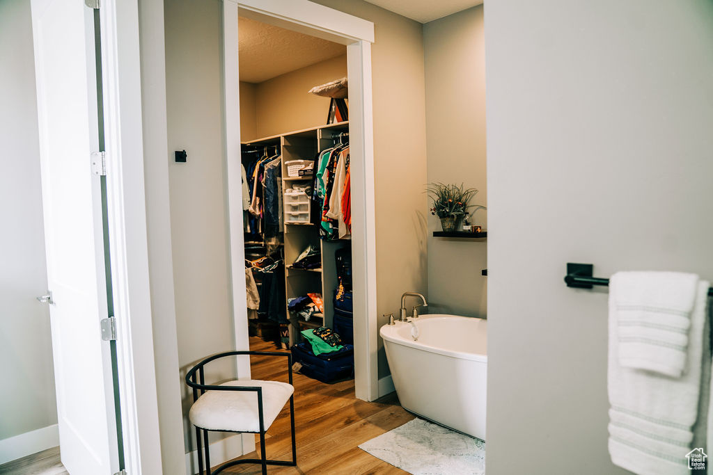 Bathroom with a freestanding tub, wood finished floors, and a spacious closet