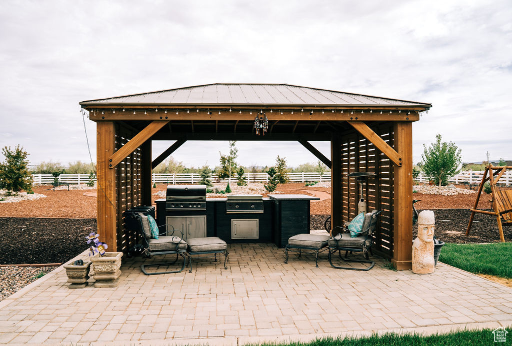 View of patio featuring a gazebo, fence, an outdoor kitchen, and area for grilling